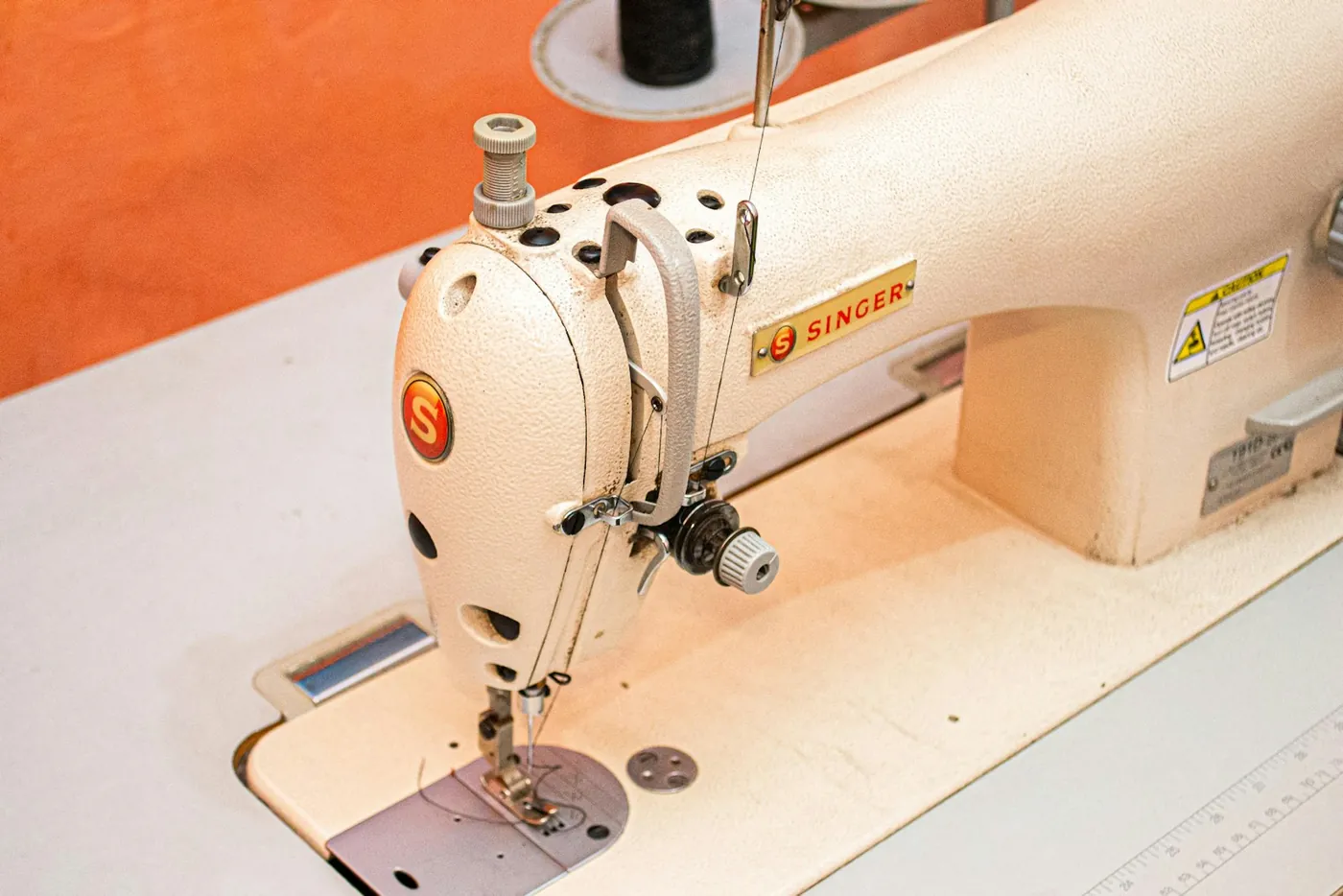 A sewing machine threaded and ready on a tailor's workbench