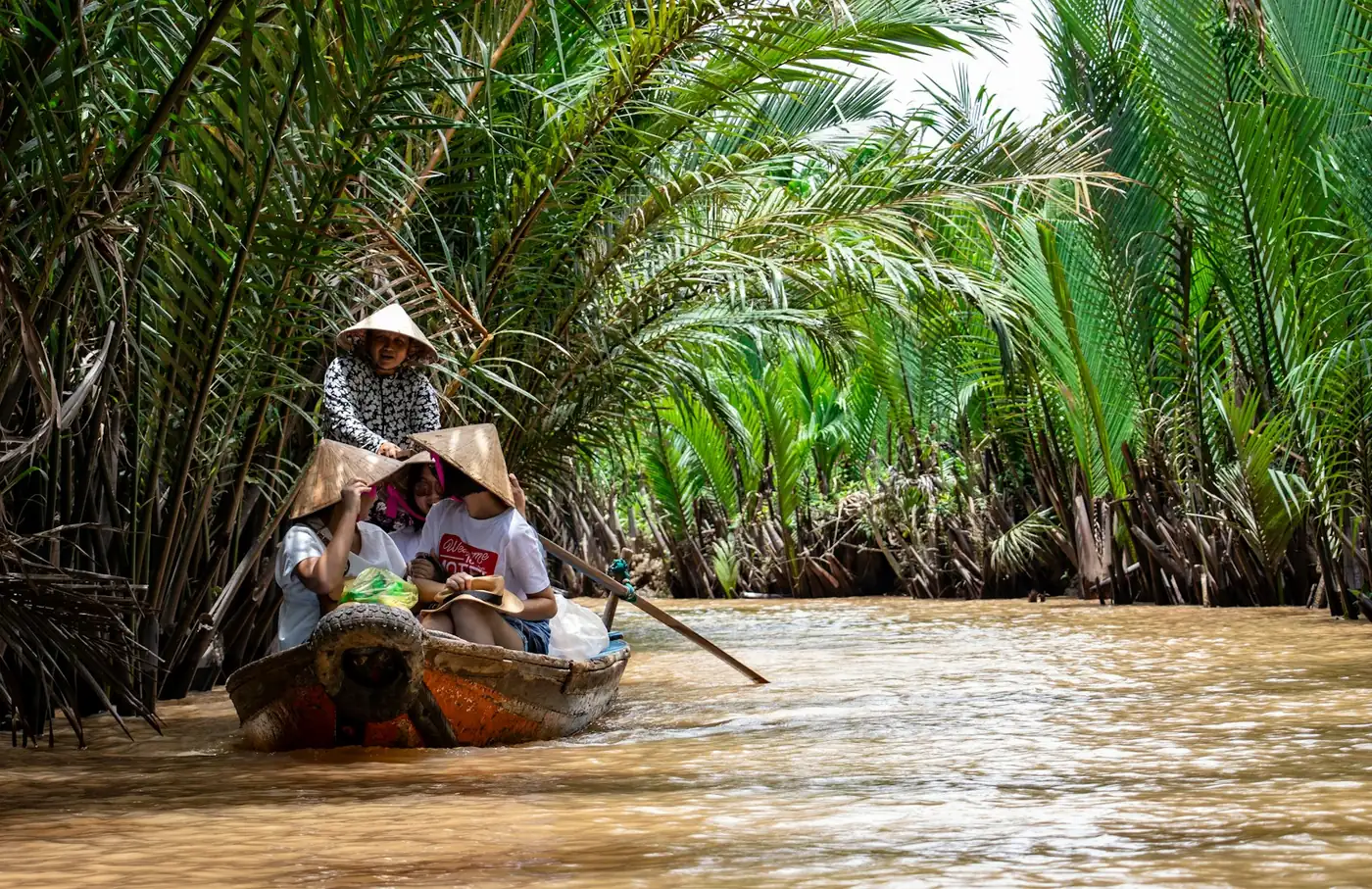 Boats on a narrow canal lined with palms in the Mekong Delta, southern Vietnam