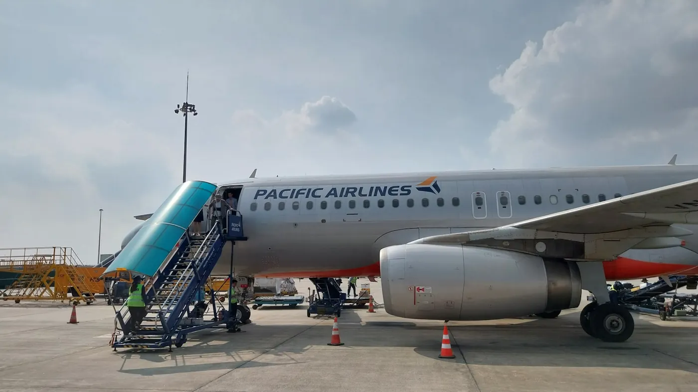 A Pacific Airlines Airbus A320 with boarding stairs and ground crew on the apron at Noi Bai airport in Hanoi, Vietnam