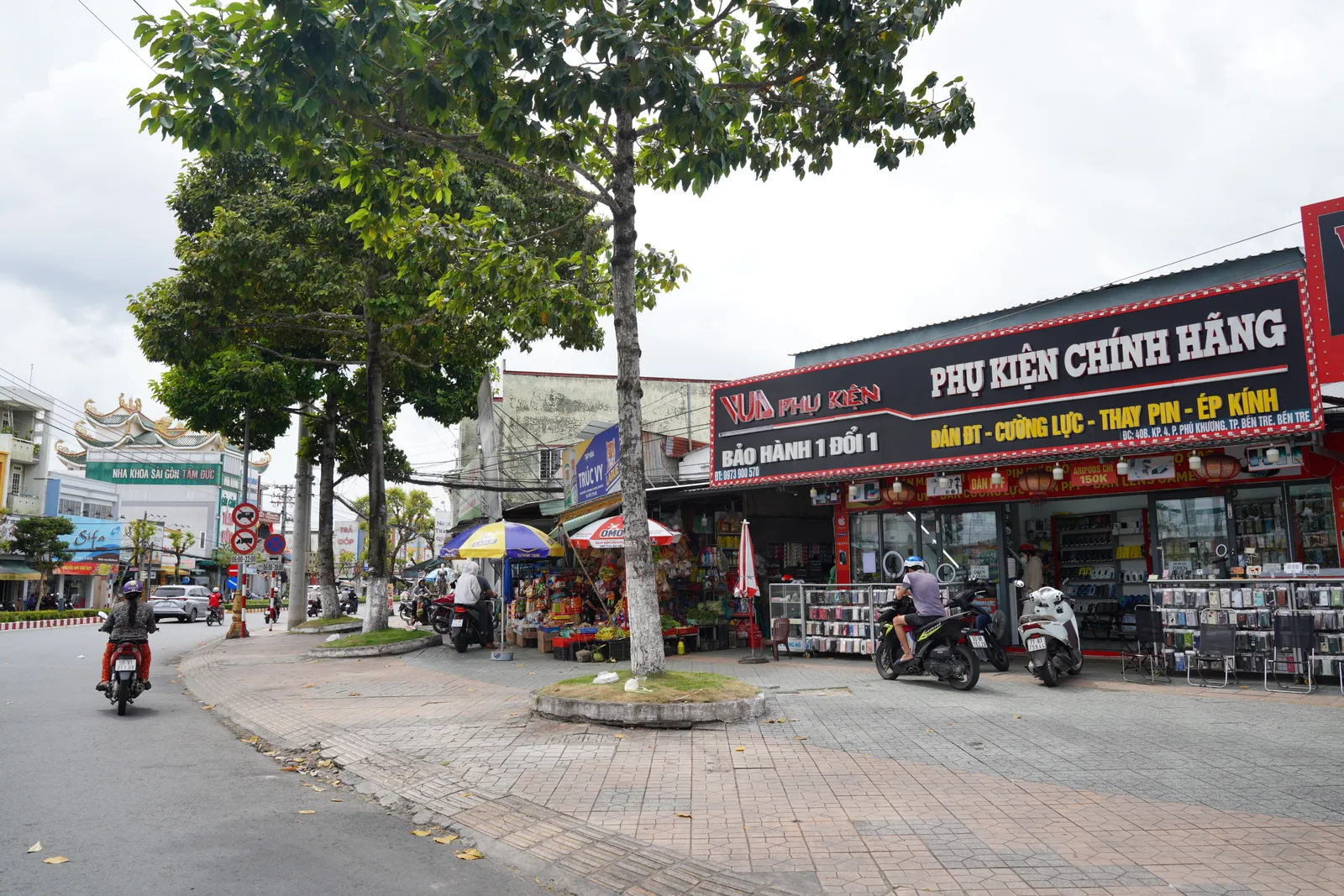A busy street full of motorbikes in a Vietnamese city seen from the pavement