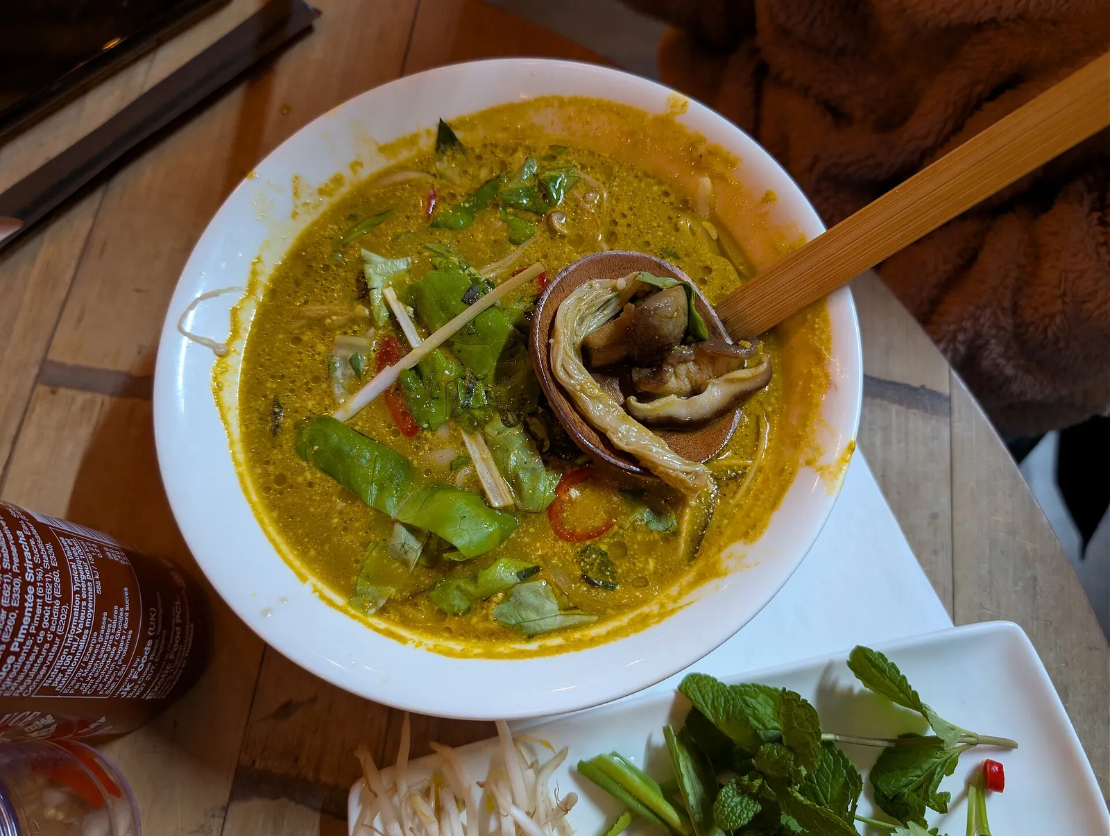 A bowl of Vietnamese pho noodle soup served with herbs on the side