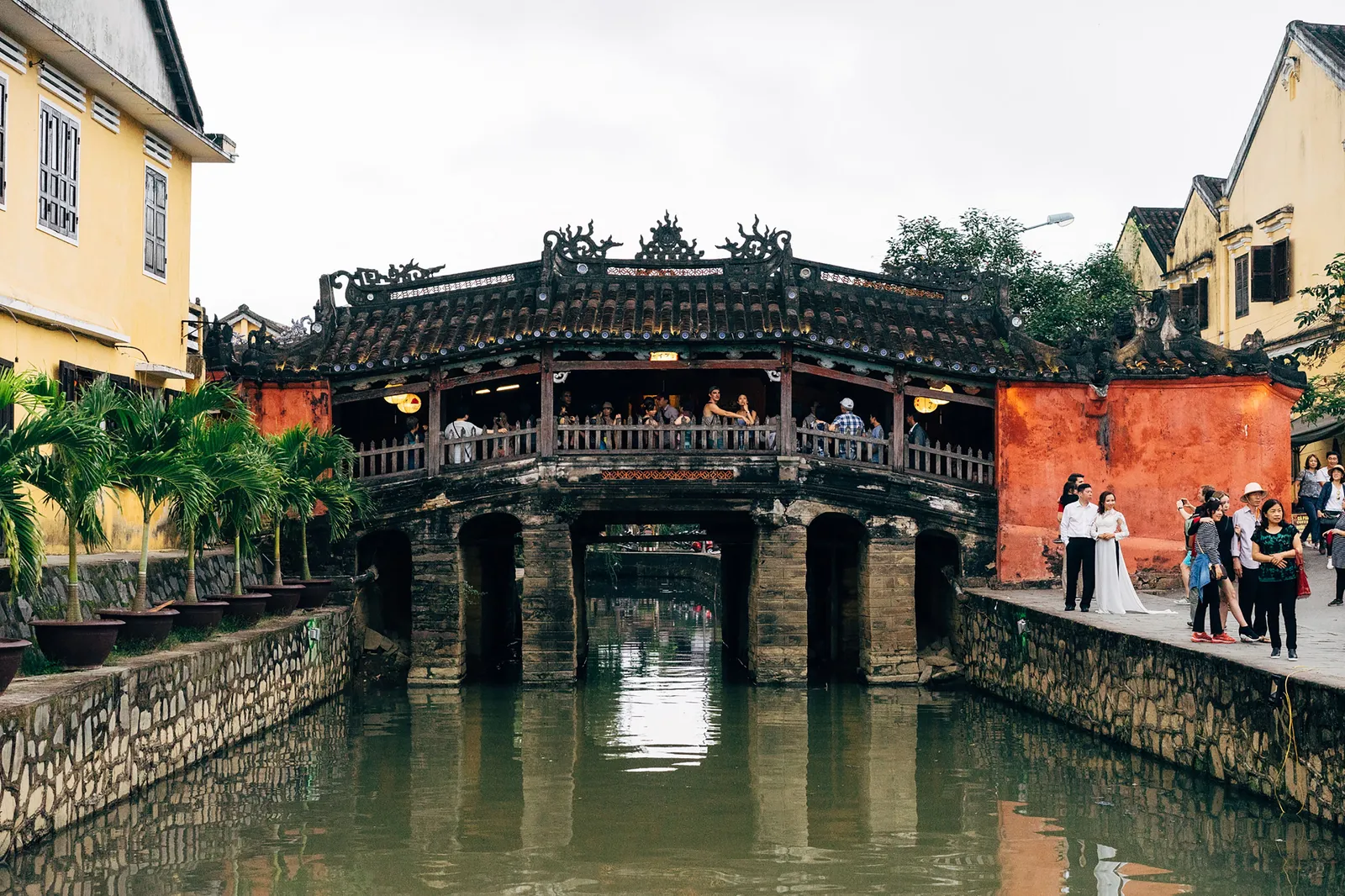 The Japanese Covered Bridge in Hoi An old town, Vietnam, with yellow-walled shophouses along the canal in daylight