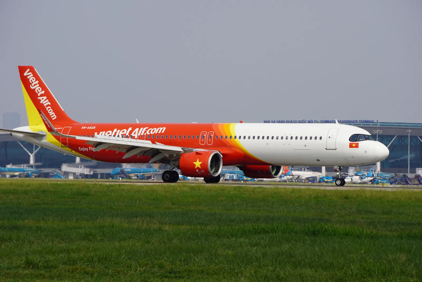 An aircraft on the apron at a Vietnamese domestic airport with the terminal building behind
