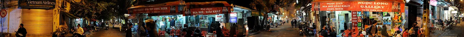 People drinking on small stools at a street beer corner in Hanoi at night, Vietnam
