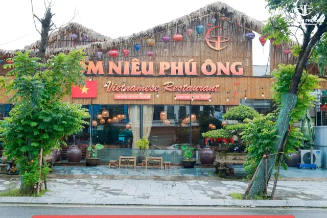 A thatched roof facade with large golden letters, colorful lanterns and clay jars at the entrance
