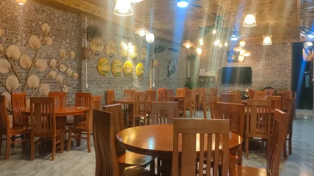 A brick hall with round wooden tables, a straw ceiling and yellow signs on the wall