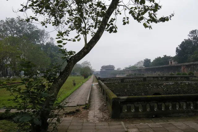 The wall of an imperial enclosure with a moat running along it, grass and woodland