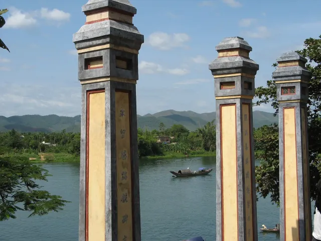 Traditional stone pillars on a riverbank with a single boat behind