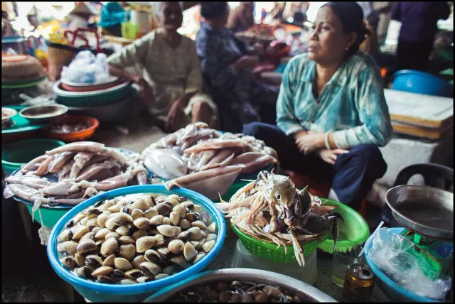 A market stall with bowls of fresh seafood and a vendor behind it