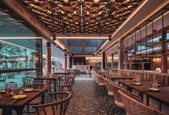 A set dining hall with an ornate wooden ceiling and windows onto the sea