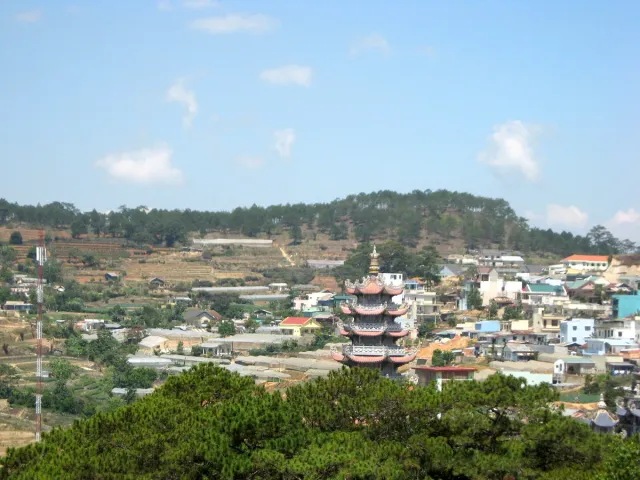 A view over a town between forested hills with pagoda spires showing through