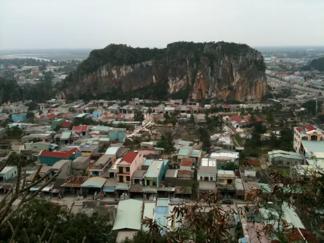 A large rock outcrop rising above a neighbourhood of low houses