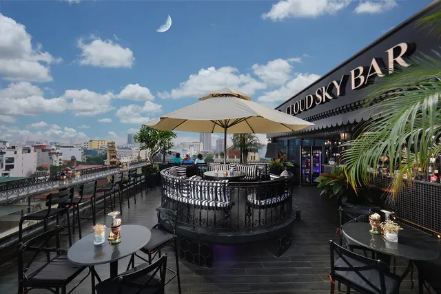 A rooftop terrace with a parasol, striped sofas and a view of the city roofs by day