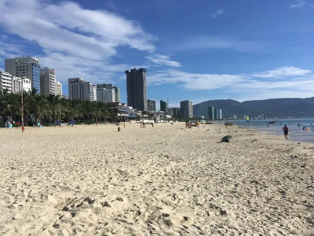 A wide strip of sand with a city skyline behind