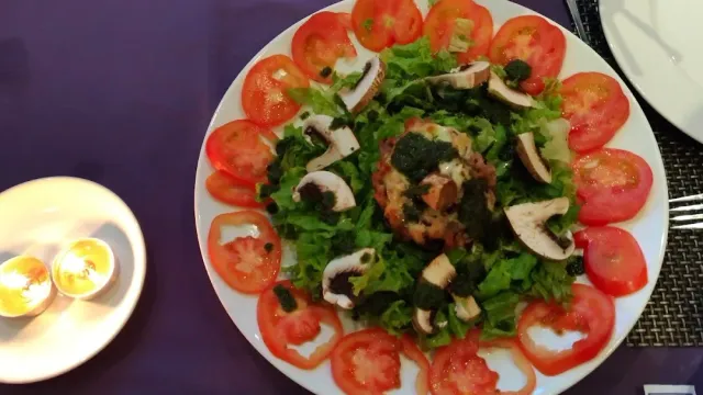 A salad plate with tomato slices arranged in a circle, cut mushrooms and green lettuce