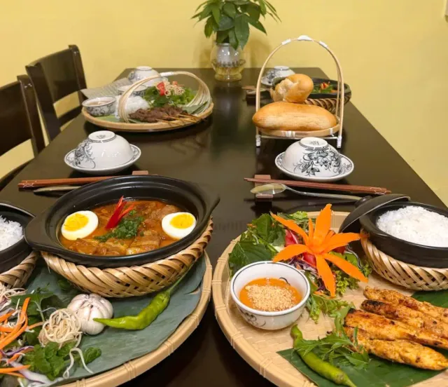 A set table with clay pots, eggs in sauce, rice and grilled skewers on bamboo trays