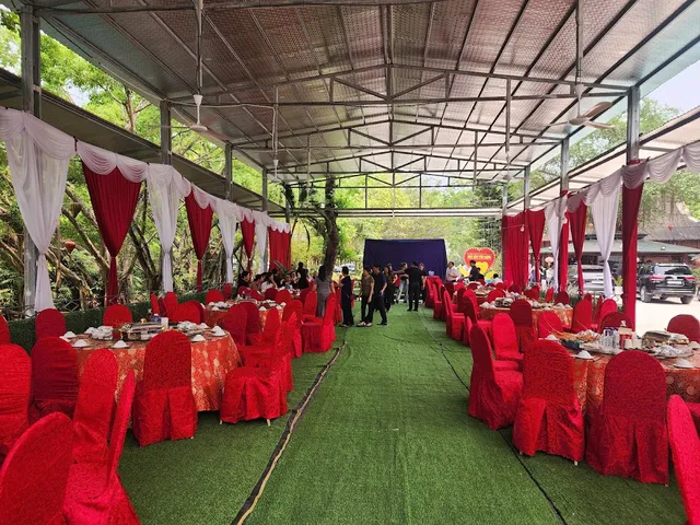 An event tent with red chairs, set tables and artificial grass in the aisle