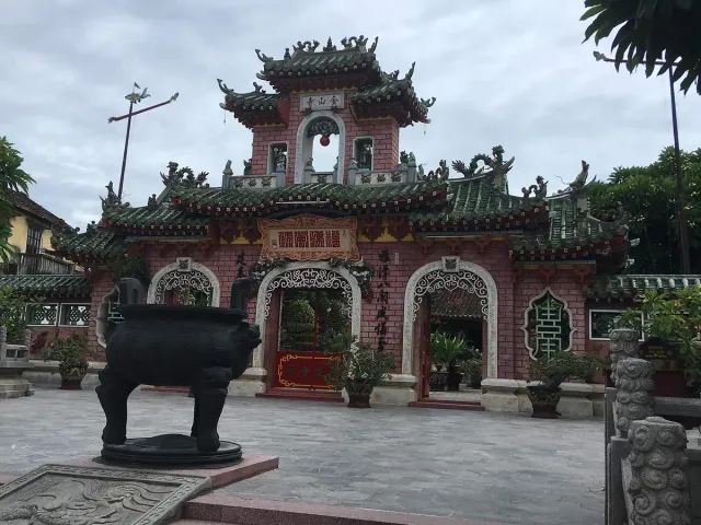 A pink Chinese assembly hall gate with a bronze incense urn in front