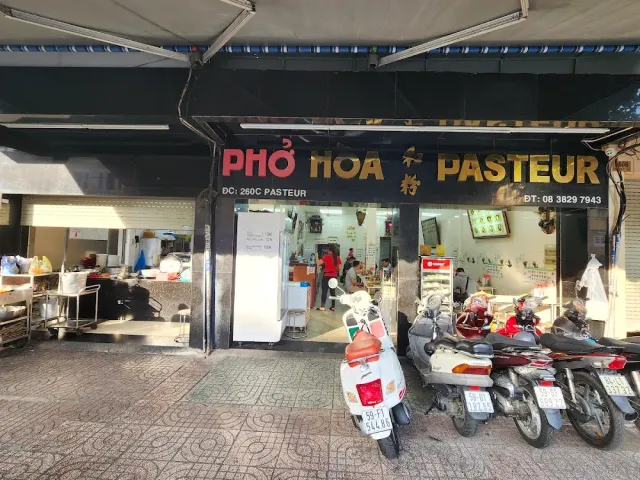 A restaurant front with a black sign and motorbikes parked on the sidewalk in front of it