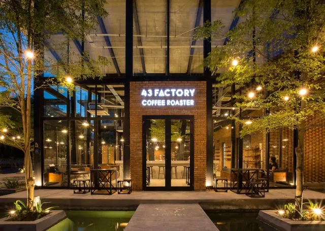 A brick facade at twilight with white letters, lit glass walls and a water pool