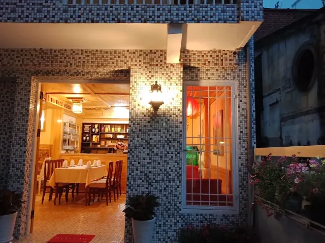 A twilight entrance with mosaic walls, and through the door set tables are visible