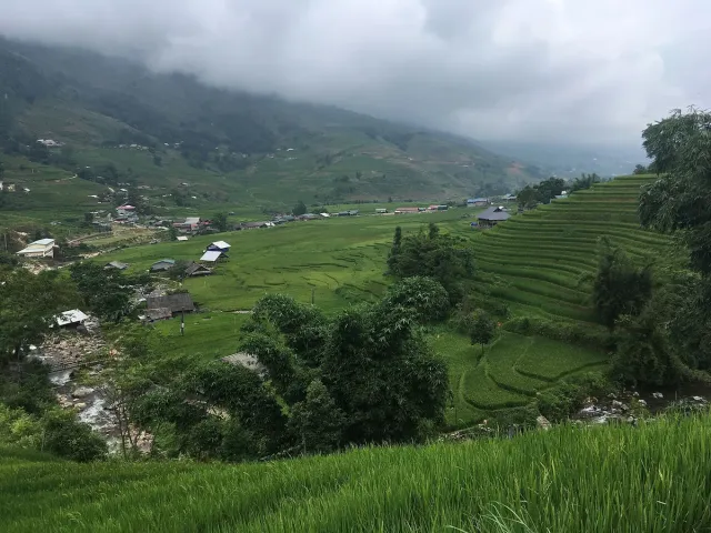 Green rice terraces on the slopes, scattered village houses and low clouds on the mountain