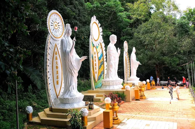 Tall white Buddha statues on a paved plaza in the heart of a green forest