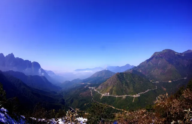 A road winding down a mountain valley under a deep blue sky