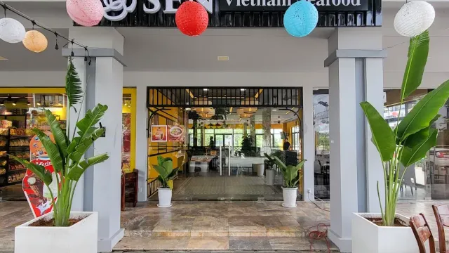 A restaurant entrance with white pillars, colorful paper lanterns and banana plants on both sides