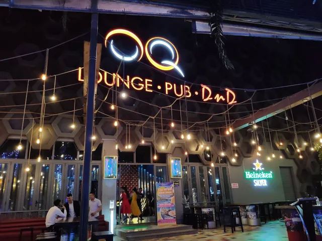 A neon sign above a pub entrance, with strings of bulbs and a hexagonal ceiling at night