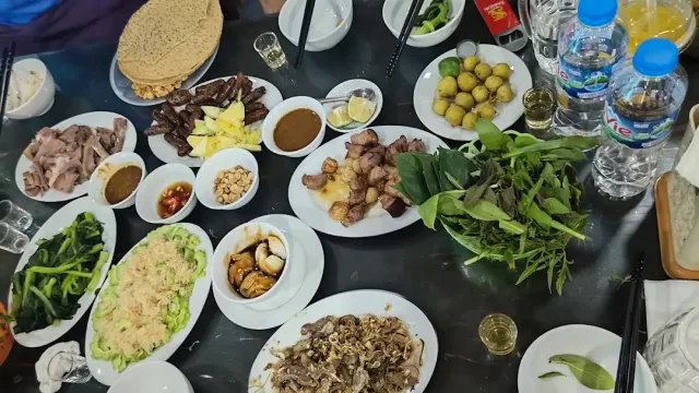 An overhead view of a table loaded with meat plates, herbs, fried rice and water bottles