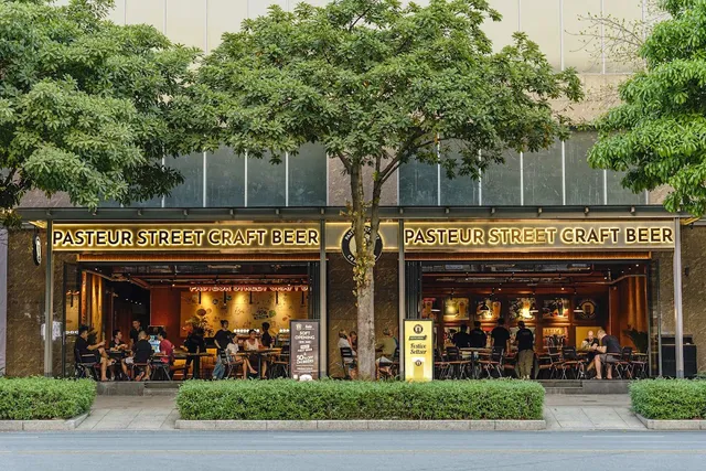 A lit storefront with a long sign, tall trees and diners seated inside
