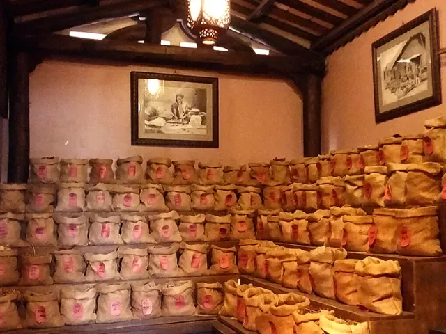 A wooden room with tiered shelves loaded with cloth sacks bearing red labels
