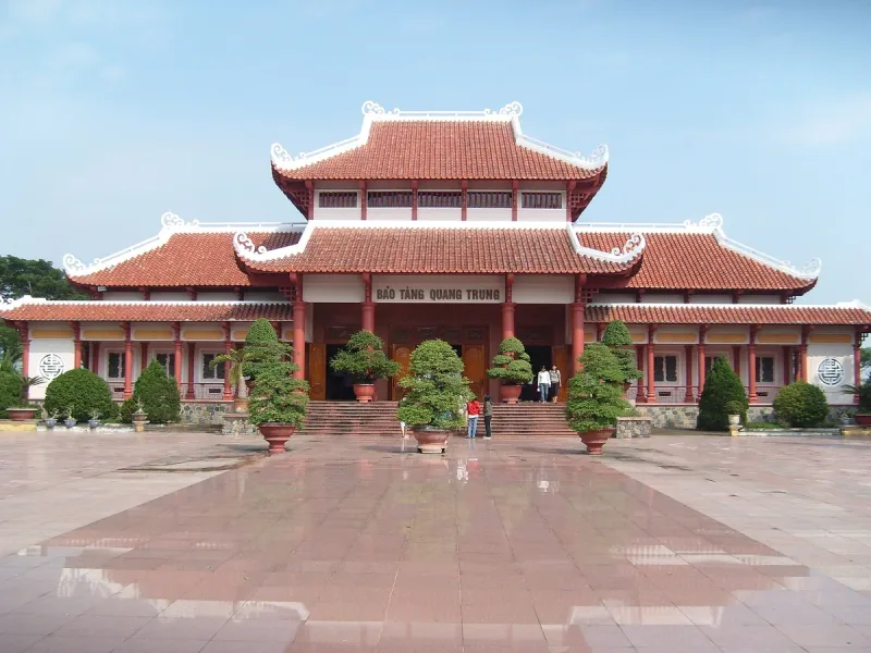 The front of the Quang Trung Museum with its curved tiled roofs and the sign above the entrance, facing a paved square