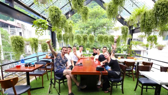 A terrace with hanging ferns and artificial grass, a group seated around a long wooden table