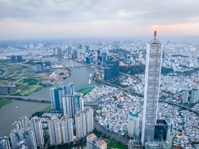 An aerial view of a dense city, a winding river and an unusually tall slender tower