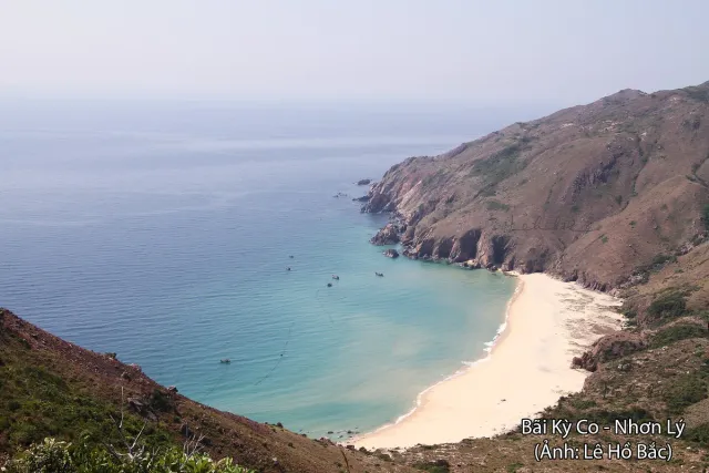 A small white sand cove between forested cliffs above blue water