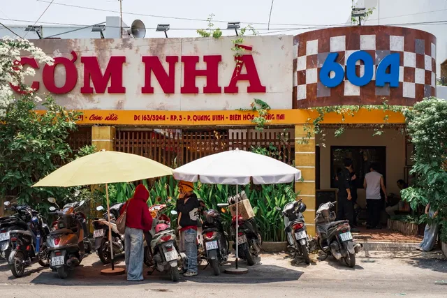 A frontage with large red letters, umbrellas and motorbikes parked on the sidewalk