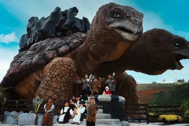 A giant turtle sculpture of artificial rock, with costumed people posing in front of it