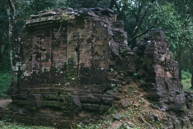 A Cham brick tower standing among trees in the forest