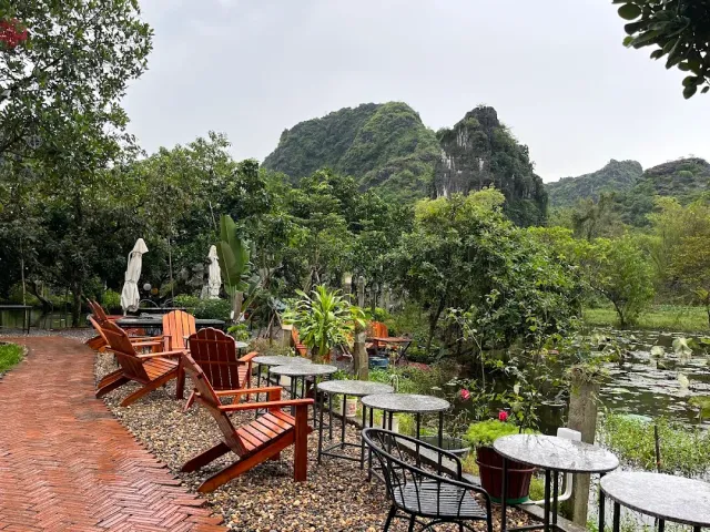 Red wooden chairs on a brick path, a lily pond and a green rock ridge behind