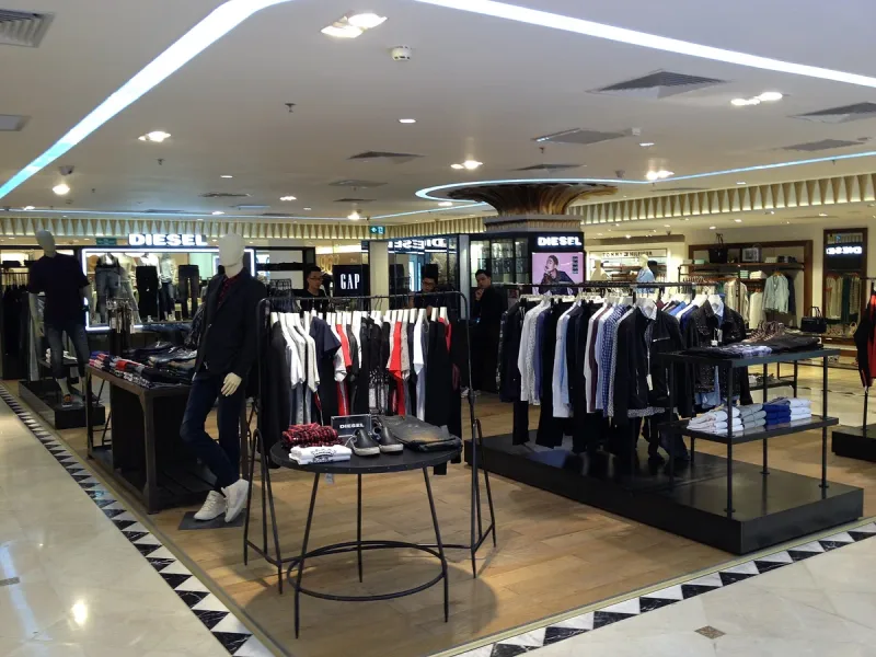 A mall fashion floor with clothing rails, mannequins and international brand storefronts