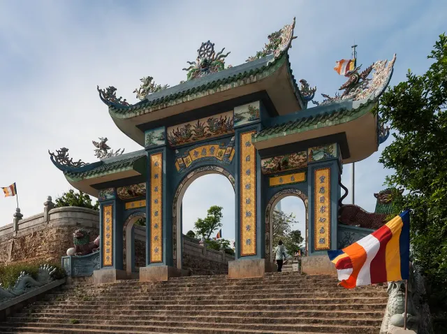 An arched temple gate with colourful banners and palm trees