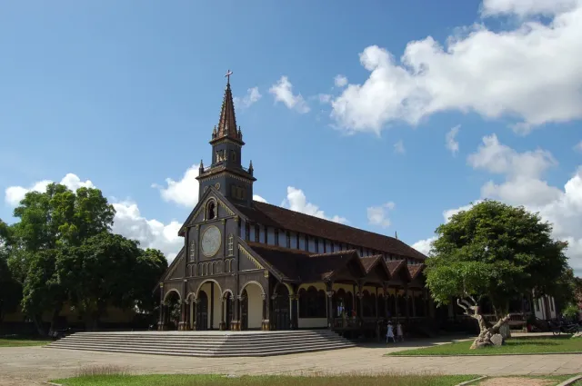 A colonial style wooden church with a pointed steeple and a lawn