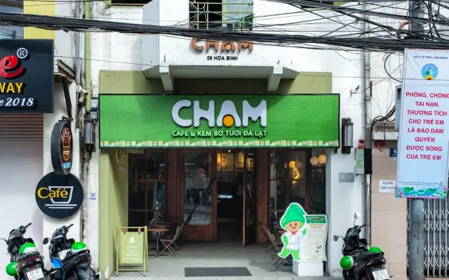 A narrow street storefront with a bright green sign, tangled power lines and parked scooters