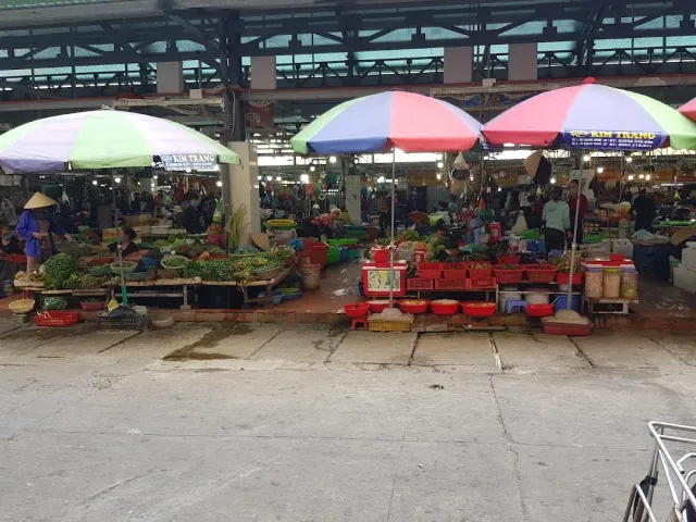 A covered hall with large striped umbrellas, vegetable stalls and red crates