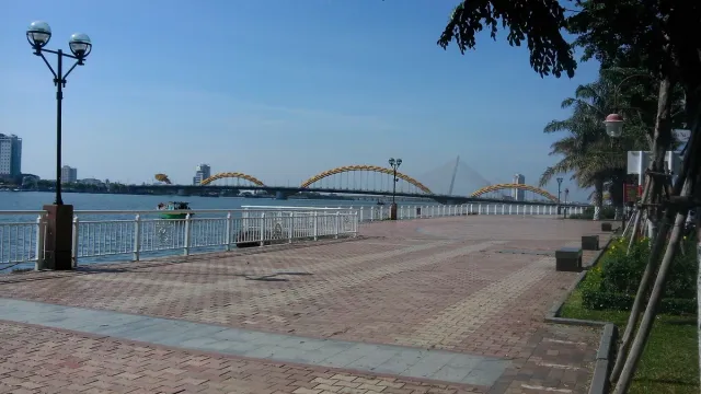 A city bridge over a wide river with a paved promenade in front