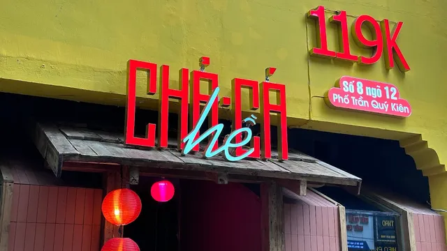 A yellow wall with a sign of large red letters and red paper lanterns beneath it