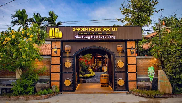 A brick gate with wooden barrels and an arch, and a paved path to a lit courtyard