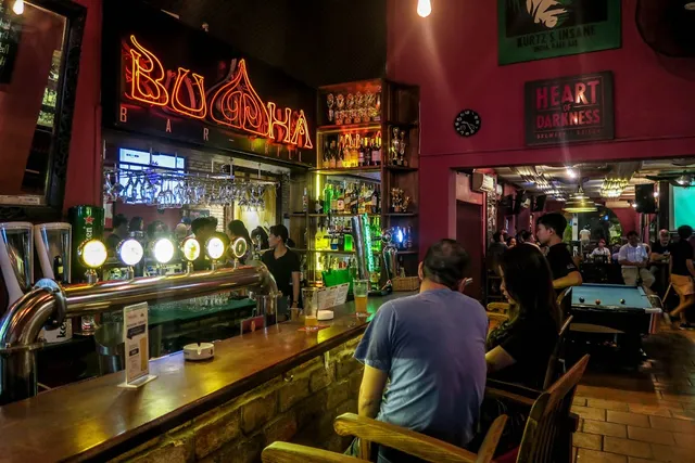 A long wooden counter with beer taps and an orange neon sign above a row of bottles
